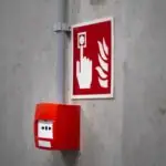 Red fire alarm button and sign on a concrete wall for emergency safety indoors.